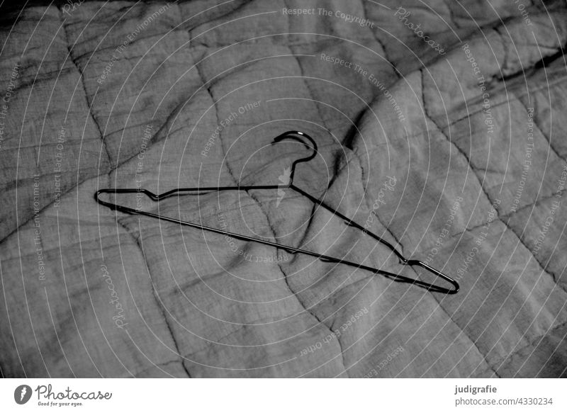 Kleiderbügel liegt auf gesteppter Leinendecke Drahtkleiderbügel Decke Bettüberwurf textil Textilien Strukturen & Formen Faltenwurf falten Linien Stoff Muster
