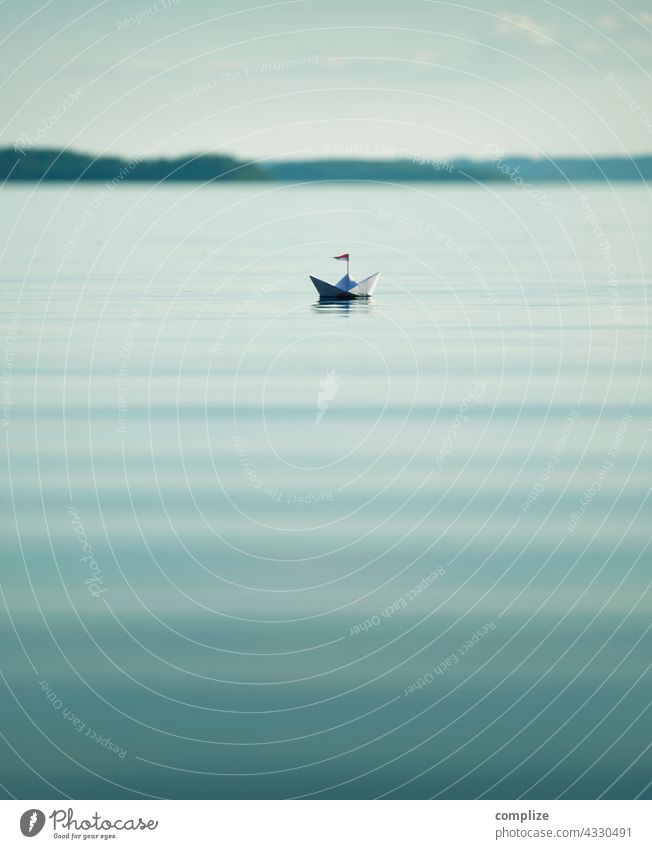 Ruhiger See mit kleinem Papierschiff Freiheit Sonnenstrahlen Sonnenlicht Küste Segelboot Ziel Schifffahrt Kindheit Strand Sommerurlaub Wasser Natur Umwelt