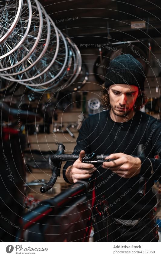 Konzentrierter Mann repariert Fahrrad in der Werkstatt fixieren Mechaniker Reparatur Lenker Dienst Meister männlich Garage beschäftigt Werkzeug Arbeit Fahrzeug