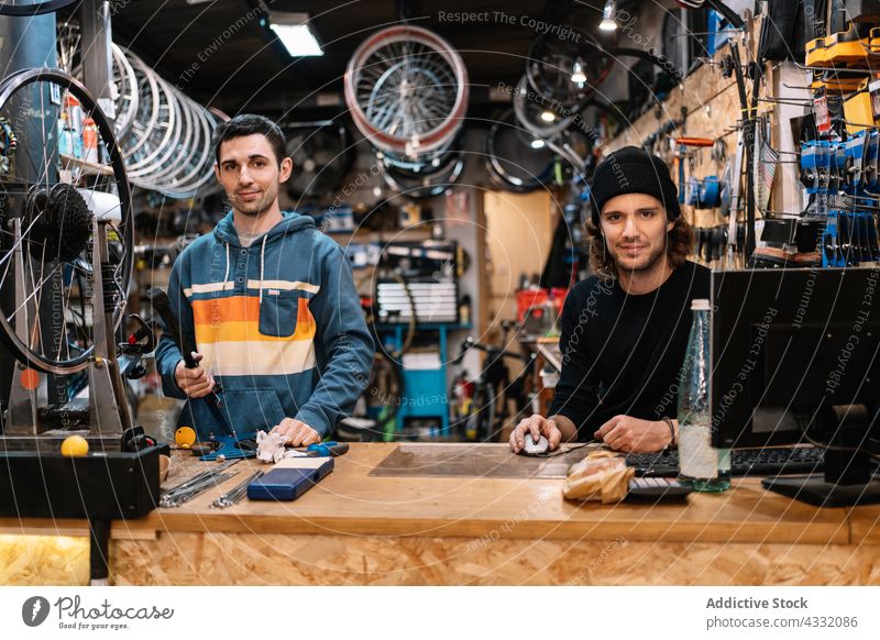 Gut gelaunte Mechaniker bei der Arbeit in der Fahrradwerkstatt Werkstatt Kollege Reparatur fixieren Dienst Männer Computer benutzend heiter Zusammensein