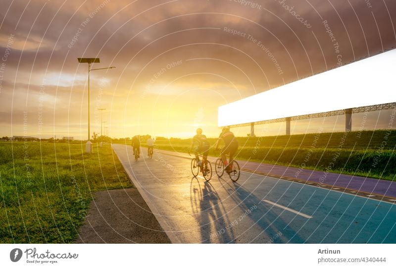 Sport Mann reiten Fahrräder auf der Straße am Abend in der Nähe von leeren Werbung Plakatwand mit Sonnenuntergang Himmel. Sommer im Freien Übung für gesunde und glückliche Leben. Radfahrer Reiten Mountainbike auf Radweg.