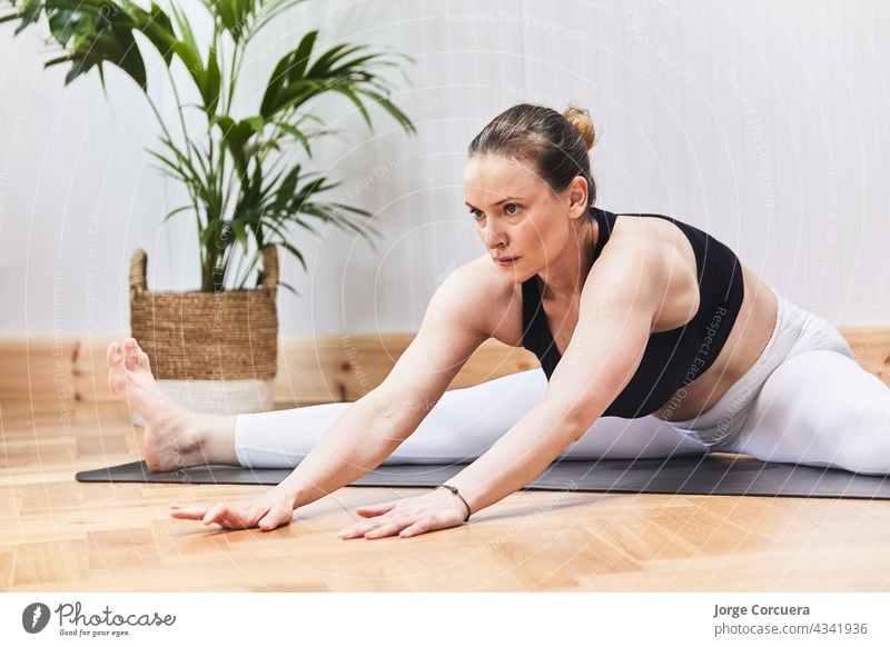 Teilausschnitt einer russischen Frau beim Üben von Yoga-Nudeln auf einer Matte Übung Pilates Körper Mädchen Training Behaarung praktizieren strecken Yogi jung