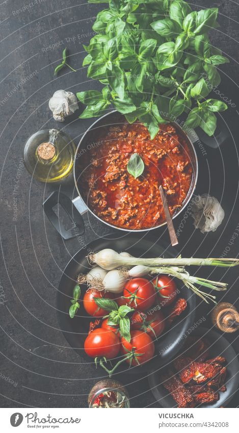 Sauce Bolognese in schwarzem Kochtopf auf dunklem Küchentisch Hintergrund mit Zutaten. Ansicht von oben Saucen dunkel Tisch Draufsicht selbstgemacht