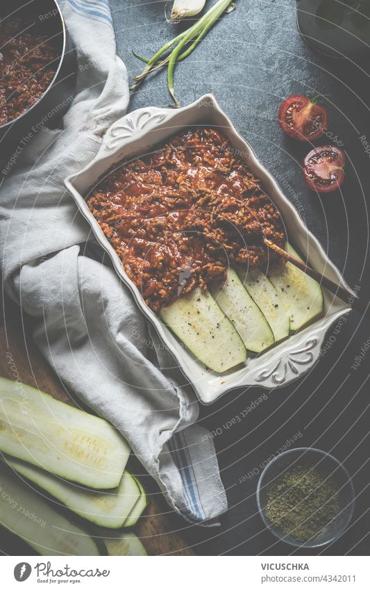 Kochen Vorbereitung von Zucchini Lasagne Bolognese auf dunklen Küchentisch mit Zutaten. Gesunde Diätkost. Ansicht von oben Essen zubereiten dunkel Tisch