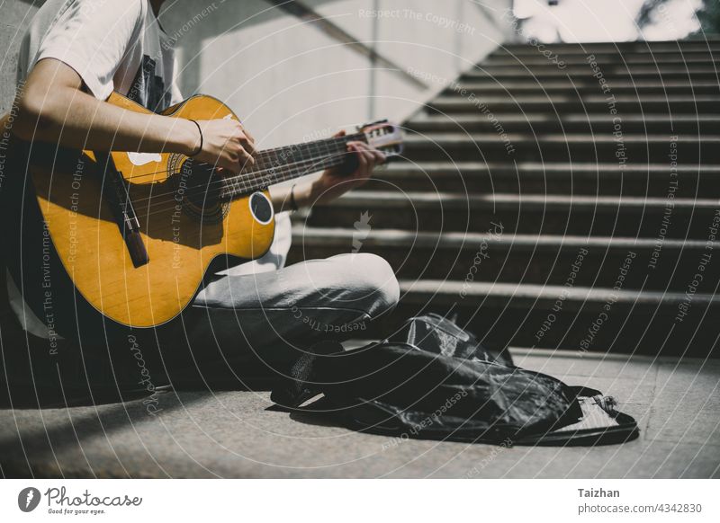 Straßenkünstler spielt Gitarre .  Junger Straßenmusiker spielt Gitarre und busking für Geld Künstler Musik Musical Musiker Künstlerin spielen Spieler Klang