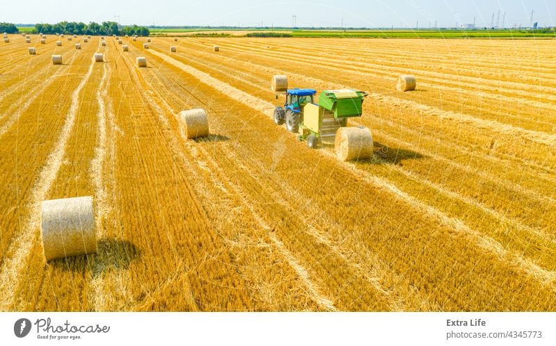 Luftaufnahme einer vom Traktor gezogenen Ballenmaschine zum Einsammeln von Stroh vom abgeernteten Feld oben Antenne landwirtschaftlich Ackerbau anbaufähig