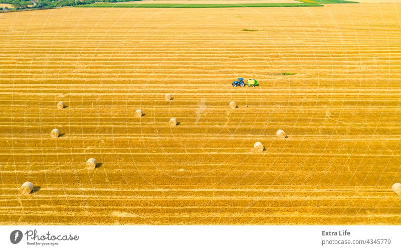 Luftaufnahme einer vom Traktor gezogenen Ballenmaschine zum Einsammeln von Stroh vom abgeernteten Feld oben Antenne landwirtschaftlich Ackerbau anbaufähig