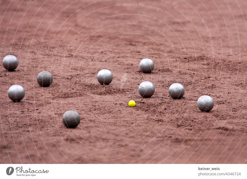 Boulekugeln auf einem Platz mit roter Erde Boule-Kugeln Boccia Boulespiel Partie Bouelplatz Turnier Sau Spielfeld Schweinchen klein groß Metall Stahlkugeln