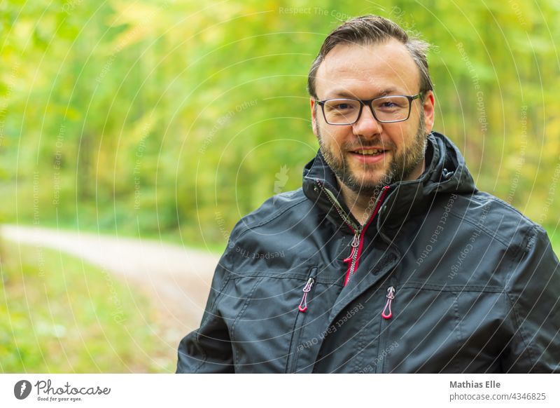 Wandern bei Regen mit Regenjacke wandern wandernd regen regenjacke Außenaufnahme schlechtes Wetter 1 herbst mann allein brille brillenträger bart lachen lächeln