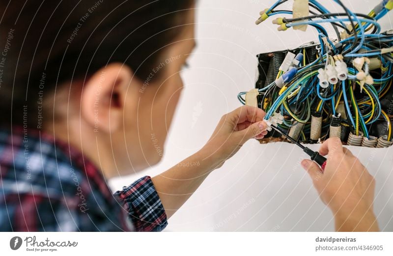 Elektriker, der an der Elektroinstallation eines Hauses arbeitet Elektrotechniker unkenntlich Frau gewelltes Rohr Schraubendreher reparierend Nahaufnahme