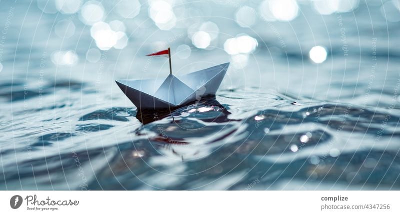 Kleines Papierschiff im Sonnenschein auf dem Meer Freiheit Sonnenstrahlen Sonnenlicht Küste Segelboot Ziel Schifffahrt Kindheit Strand Sommerurlaub Wasser Natur