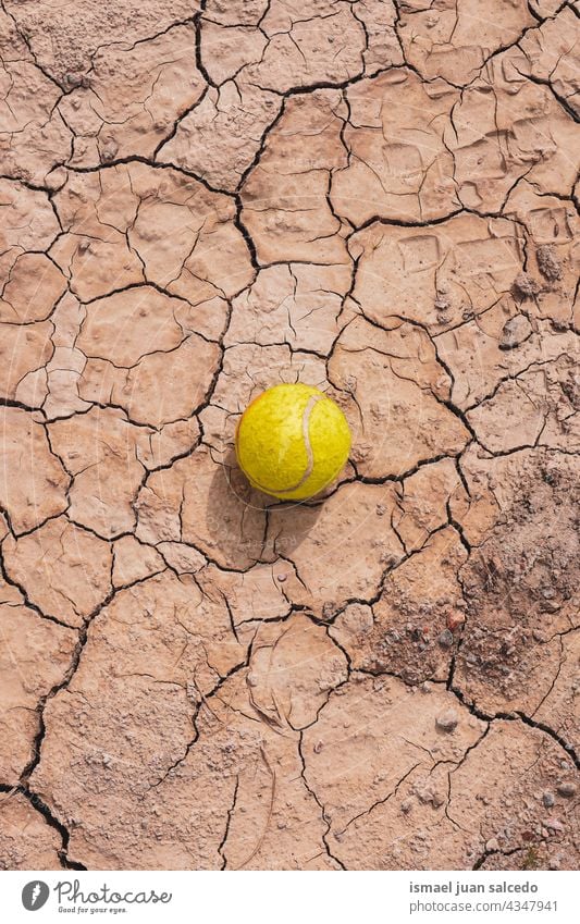 gelber Tennisball auf dem Dessertboden Ball Sport Objekt Stillleben braun alt Verlassen Boden Land trocknen texturiert Erde Natur wüst Klima Muster Schmutz