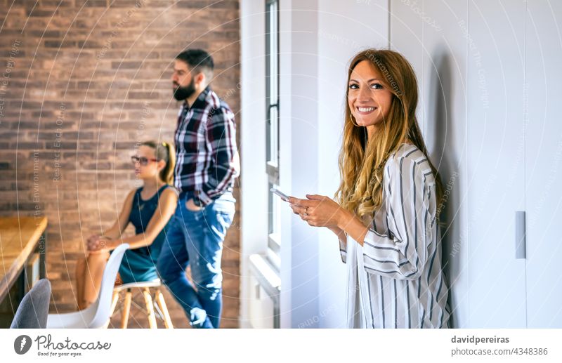 Glückliche Geschäftsfrau schaut in die Kamera im Büro Frau Porträt schauende Kamera Coworking Textfreiraum Kollege Business Sitzung Stehen arbeiten Tablette