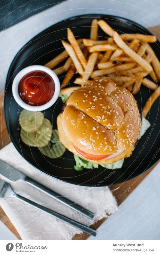 Draufsicht auf einen traditionellen American Cheeseburger mit Pommes frites Amerikaner Hintergrund Barbecue grillen Rindfleisch groß Brot Brötchen Burger