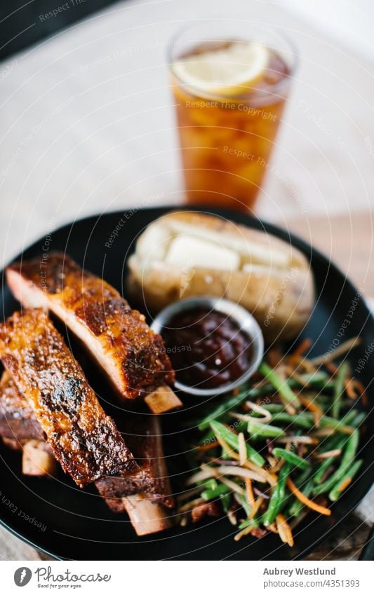 Rippchen mit grünen Bohnen und Kartoffeln auf einer Tischdecke aus Leinen im Landhausstil Amerikaner Hintergrund gebacken Ofenkartoffel Barbecue gegrillt