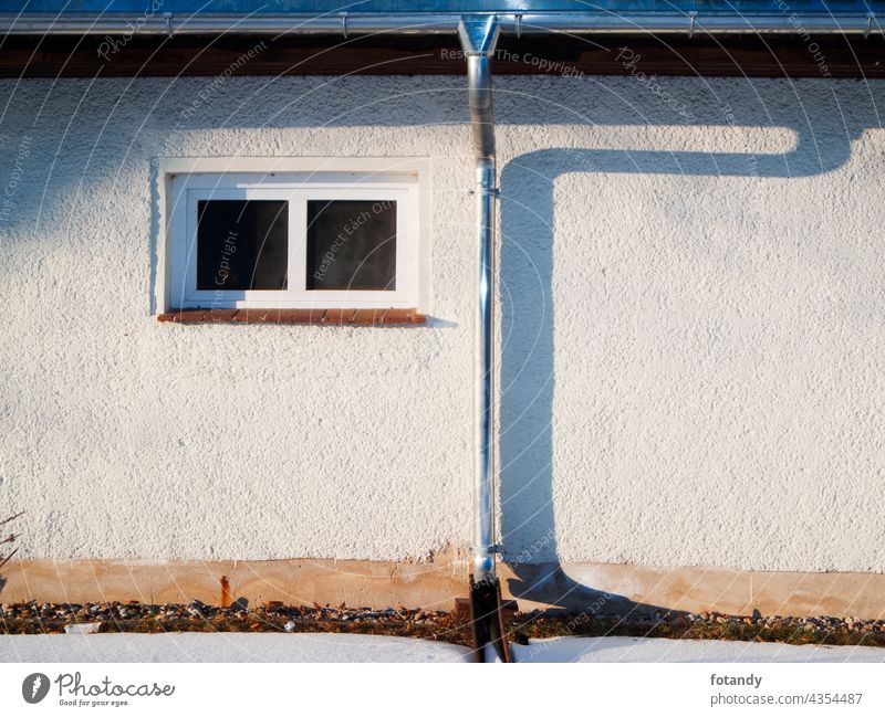 Hauswand mit Regenrinne und Fallrohr Zauberstab Außenseite Gebäude fenster www. niemand Draussen Metall Installation Schatten Abendsonne Sonnenlicht Rauputz