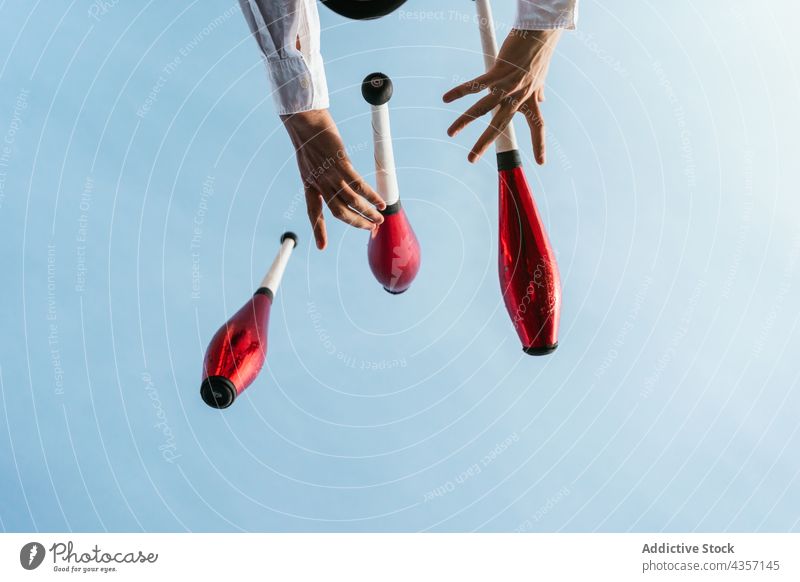 Jongleur mit Zirkustrick vor blauem Himmel jonglieren Trick Künstler ausführen Club Hand unterhalten Talent Kunst Fähigkeit Aktivität zeigen farbenfroh üben