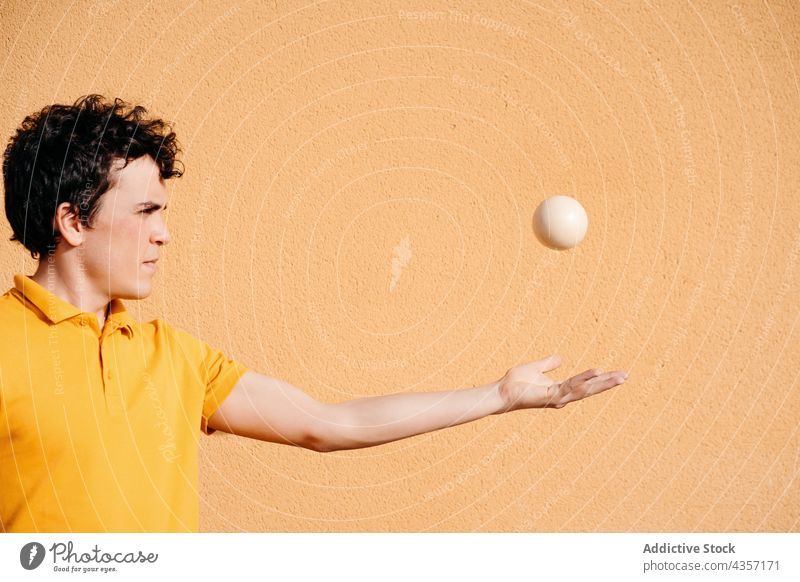 Agiler Mann jongliert Bälle in der Nähe einer bunten Wand jonglieren Trick Ball ausführen farbenfroh urban Talent Fähigkeit unterhalten männlich Kunst Aktivität