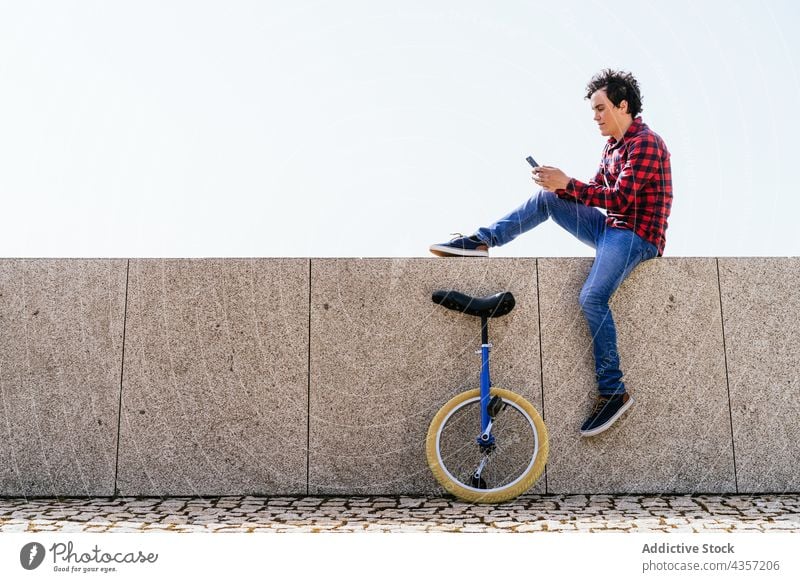 Junger Mann mit Einrad und Smartphone auf der Straße benutzend Telefon urban modern Mobile online Apparatur männlich jung Rad Surfen Kommunizieren Funktelefon