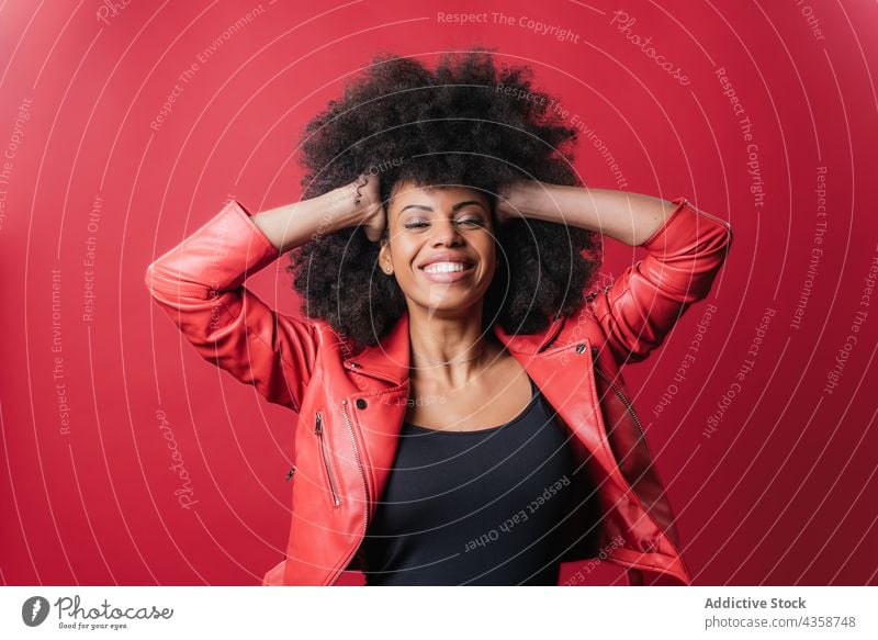 Rebellische schwarze Frau schreit und berührt lockiges Haar auf rotem Hintergrund auflehnen unanständig schreien Schrei Stil laut Afro-Look expressiv