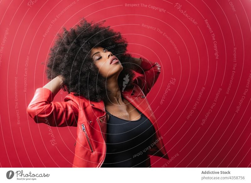 Rebellische schwarze Frau schreit und berührt lockiges Haar auf rotem Hintergrund auflehnen unanständig schreien Schrei Stil laut Afro-Look expressiv