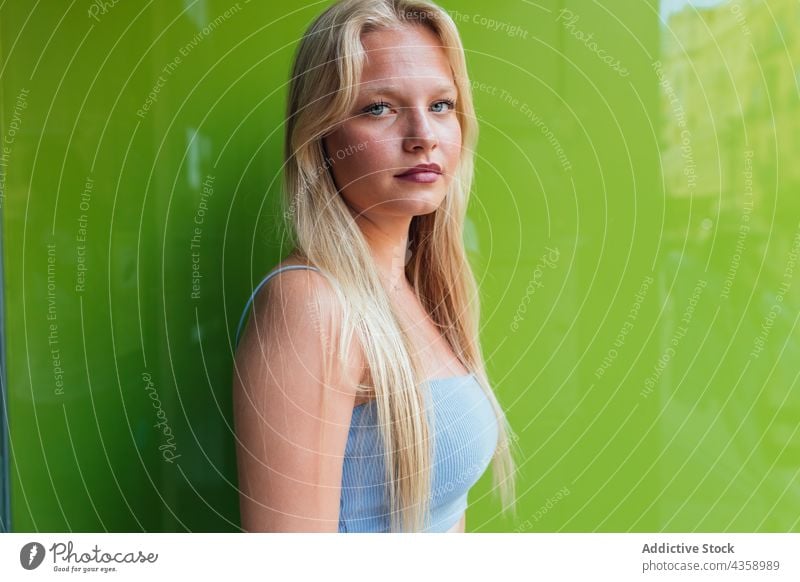 Charmante Frau zwinkert der Kamera auf grünem Hintergrund zu blond charmant Stil trendy Schönheit positiv Glück feminin lange Haare modern sorgenfrei Vorschein