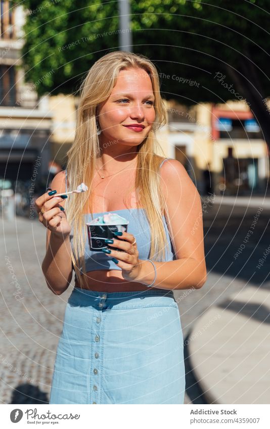 Frau isst Eis auf der Straße im Sommer Speiseeis essen Großstadt Erfrischung kalt geschmackvoll Dessert lecker blond jung süß stehen Lebensmittel hübsch