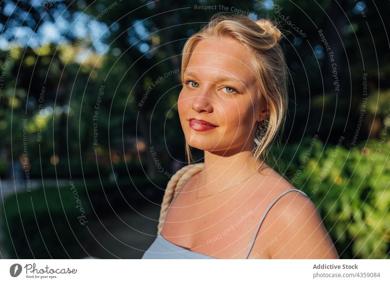 Junge Frau im Sommerpark stehend Park sonnig charmant Schönheit Vorschein schön Lächeln Sonnenlicht positiv hübsch tausendjährig jung Natur Glück blond Freude