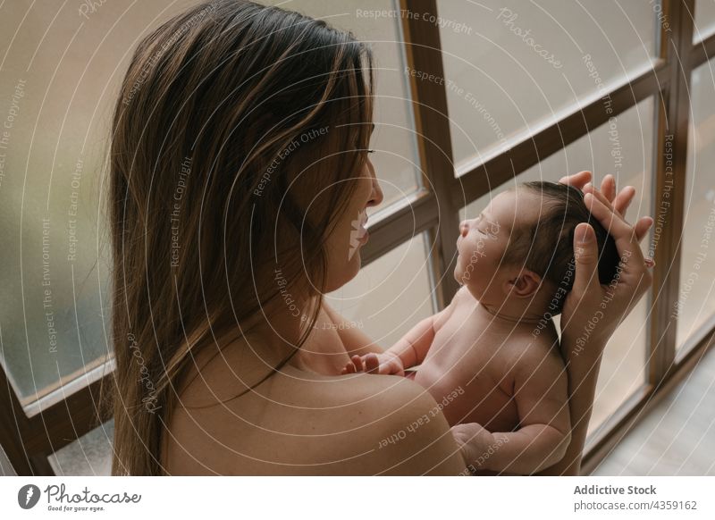 Sanfte Mutter mit schlafendem Neugeborenen zu Hause neugeboren Säugling nackt Zusammensein Liebe Angebot Baby Pflege bezaubernd niedlich heimwärts Kind Fenster