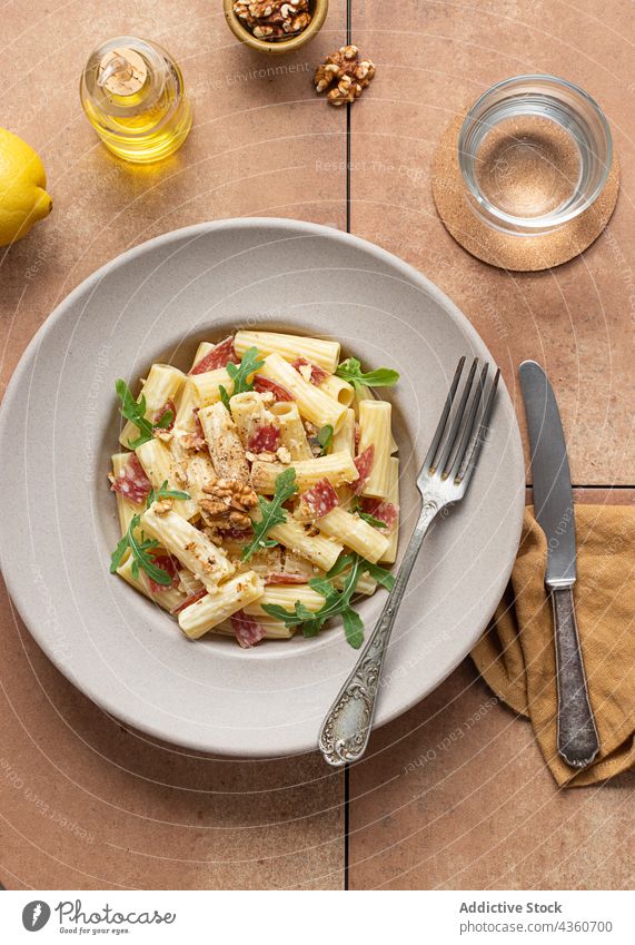 Nudelgericht mit Rucola, Salami und Walnüssen rigatoni Spätzle Speise Walnussholz Salatbeilage Sommer Draufsicht Zitrone mediterran frisch lecker abschließen