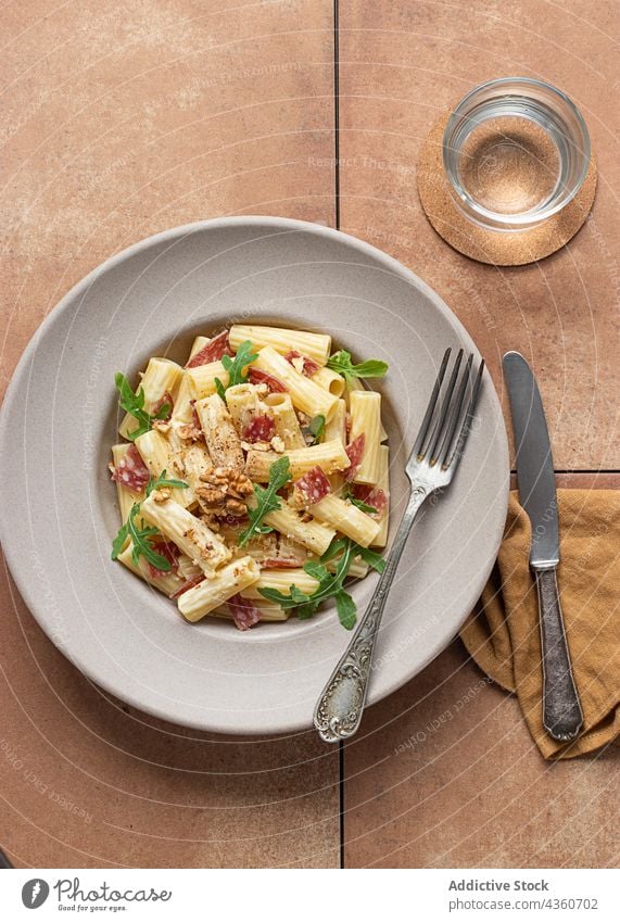 Nudelgericht mit Rucola, Salami und Walnüssen rigatoni Spätzle Speise Walnussholz Salatbeilage Sommer Draufsicht Zitrone mediterran frisch lecker abschließen