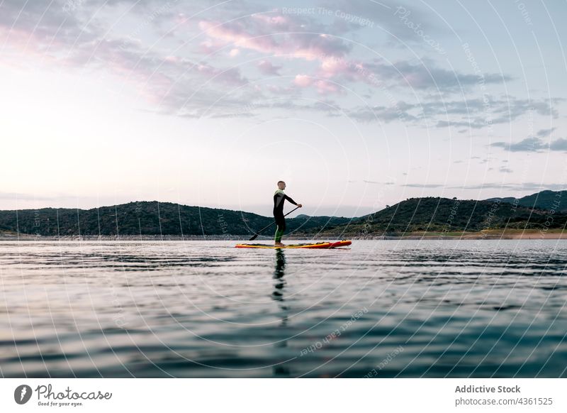 Unbekannter Mann schwimmt auf Paddleboard im Meer Surfer Paddelbrett Zusatzplatine Schwimmer MEER Sonnenuntergang Sommer Holzplatte männlich Wasser Aktivität