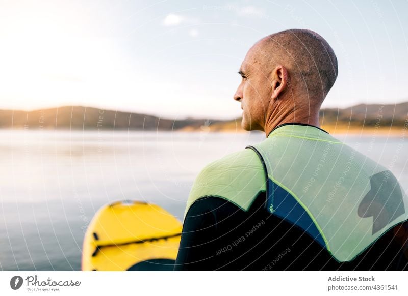 Mann auf Paddelbrett schwimmt auf See Holzplatte Sport knien Aktivität üben Schwimmer männlich aktiv sportlich Erwachsener Wassersport Hobby Erholung schwimmen