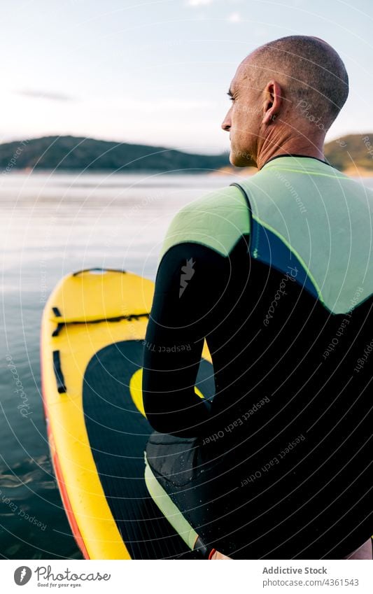 Mann auf Paddelbrett schwimmt auf See Holzplatte Sport knien Aktivität üben Schwimmer männlich aktiv sportlich Erwachsener Wassersport Hobby Erholung schwimmen