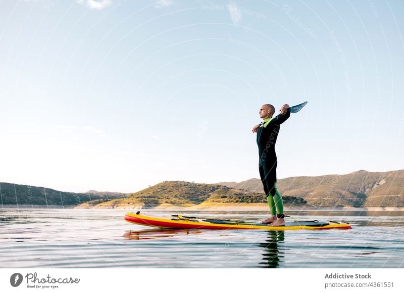 Männlicher Surfer steht auf einem Paddleboard im Meer Mann Paddelbrett Zusatzplatine MEER Gelassenheit Sonnenuntergang Abend Sommer männlich Schwimmer