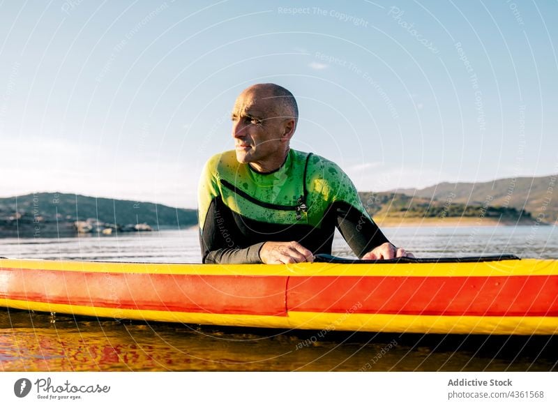 Mann übt Paddleboarding im Wasser eines Sees Paddel Holzplatte Lügen schwimmen Paddelbrett Aktivität üben Wassersport sportlich ruhen Schwimmer männlich aktiv