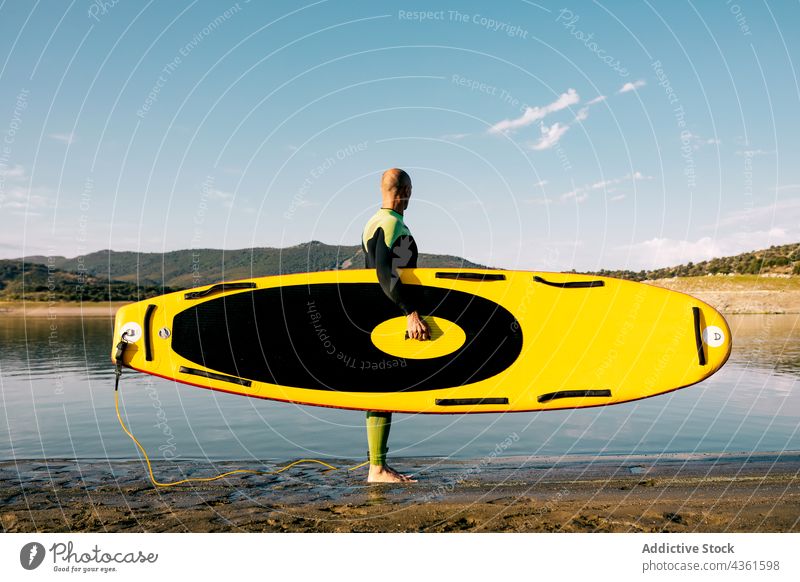 Anonymer Mann mit Paddleboard im Meerwasser Paddelbrett MEER Zusatzplatine Neoprenanzug Surfer Surfbrett Wasser Sport männlich Aktivität Hobby aktiv Schwimmer