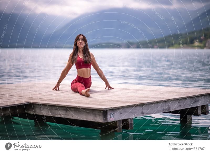 Flexible Frau in Front-Split-Pose sitzend und Yoga machend Dehnung beweglich Pier See üben ruhig Windstille Asana hanumanasana Harmonie Wasser Gelassenheit Kai