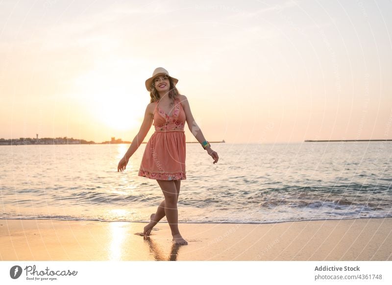 Junge Frau hat Spaß am Strand bei Sonnenuntergang Sommer MEER Glück sorgenfrei Spaß haben Stil Urlaub Reisender Barfuß Sand Feiertag winken reisen genießen Ufer