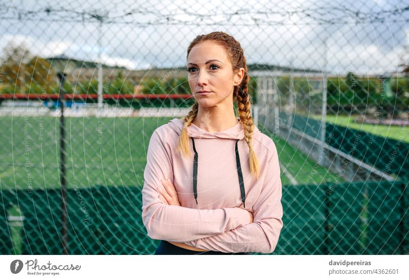 Seriöse Sportlerin mit Boxerzöpfen posiert mit verschränkten Armen ernst Frau Athlet verschränkte Arme Boxerflechten zur Seite schauend Frauenpower harte Frau