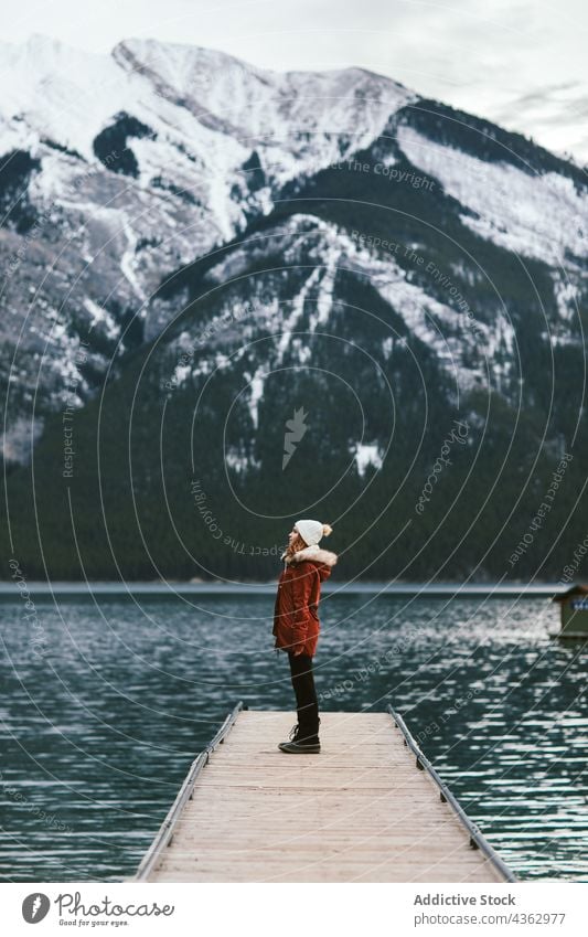 Frau steht auf Seebrücke gegen Berge Reisender Pier Berge u. Gebirge Kamm Wasser Ufer Winter Ausflug Minnewanka-See Banff National Park Alberta Kanada Natur