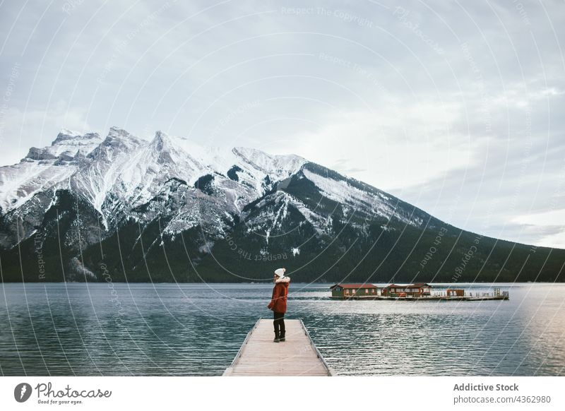 Frau steht auf Seebrücke gegen Berge Reisender Pier Berge u. Gebirge Kamm Wasser Ufer Winter Ausflug Minnewanka-See Banff National Park Alberta Kanada Natur