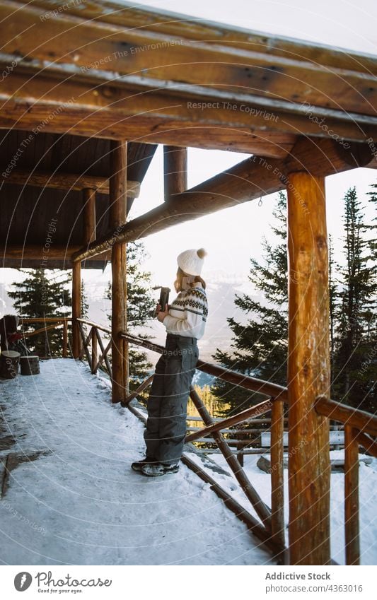 Unbekannte Frau trinkt heißes Getränk in der Nähe von verschneiten Bergen Heißgetränk Reisender Berge u. Gebirge Schnee Wartehäuschen Winter Thermoskanne