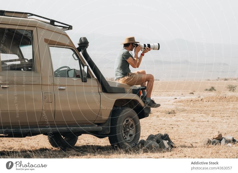 Reisender Fotograf macht Fotos während einer Safari reisen Mann fotografieren Fotoapparat Fotografie Telebild Linse männlich Offroad Geländewagen PKW Abenteuer