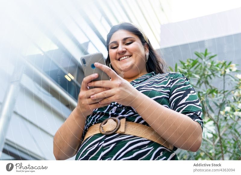 Glückliche junge Frau benutzt Smartphone auf der Straße benutzend urban Telefon Nachricht modern Stil Kommunizieren kurvenreich Mobile Browsen Apparatur Gerät