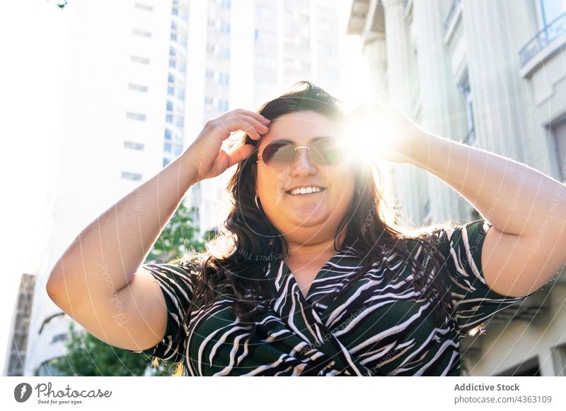 Stilvolle Frau mit Sonnenbrille auf einer Straße in der Stadt trendy Mode Sommer urban Kleid kurvenreich Aussehen jung Übergröße Brille Outfit drucken