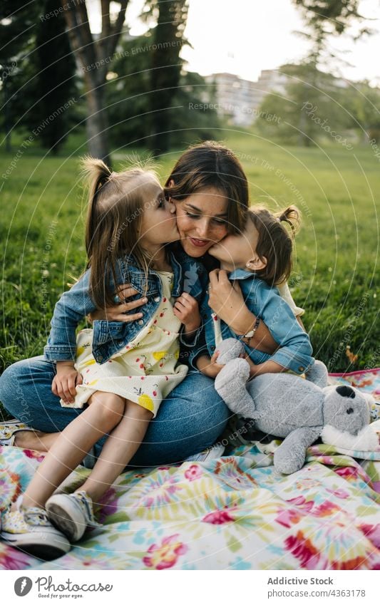 Liebevolle Mutter mit Kindern im grünen Park Kuss Zusammensein Glück Tochter Sommer Geschwisterkind niedlich kuscheln Mama Partnerschaft wenig Schwester Bonden