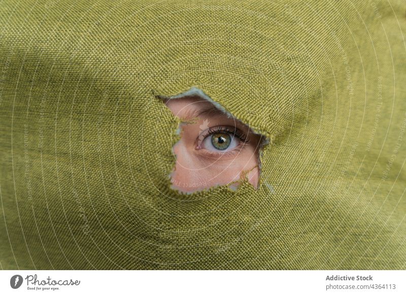 Frau mit grünen Augen schaut durch ein Loch im Stoff grüne Augen Farbe Starrer Blick starren Tierhaut Golfloch Mysterium Schönheit Deckblatt jung feminin gucken