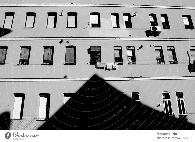 Schatten eines Dachgiebel zeigt auf ein offenes Fenster mit Wäscheleine Hauswand trocknen Wand Häusliches Leben Stadt Wäsche waschen hängen Alltagsfotografie