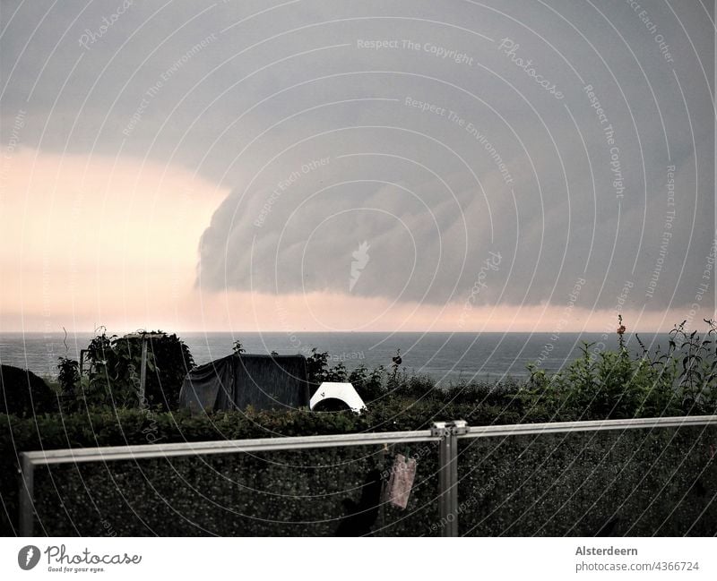 Blick von der Steilküste an der Ostsee auf das Wasser am Horizont braut sich ein Gewitter zusammen es fällt bereits Regen die Sonne ist hinter den Wolken zu erkennen